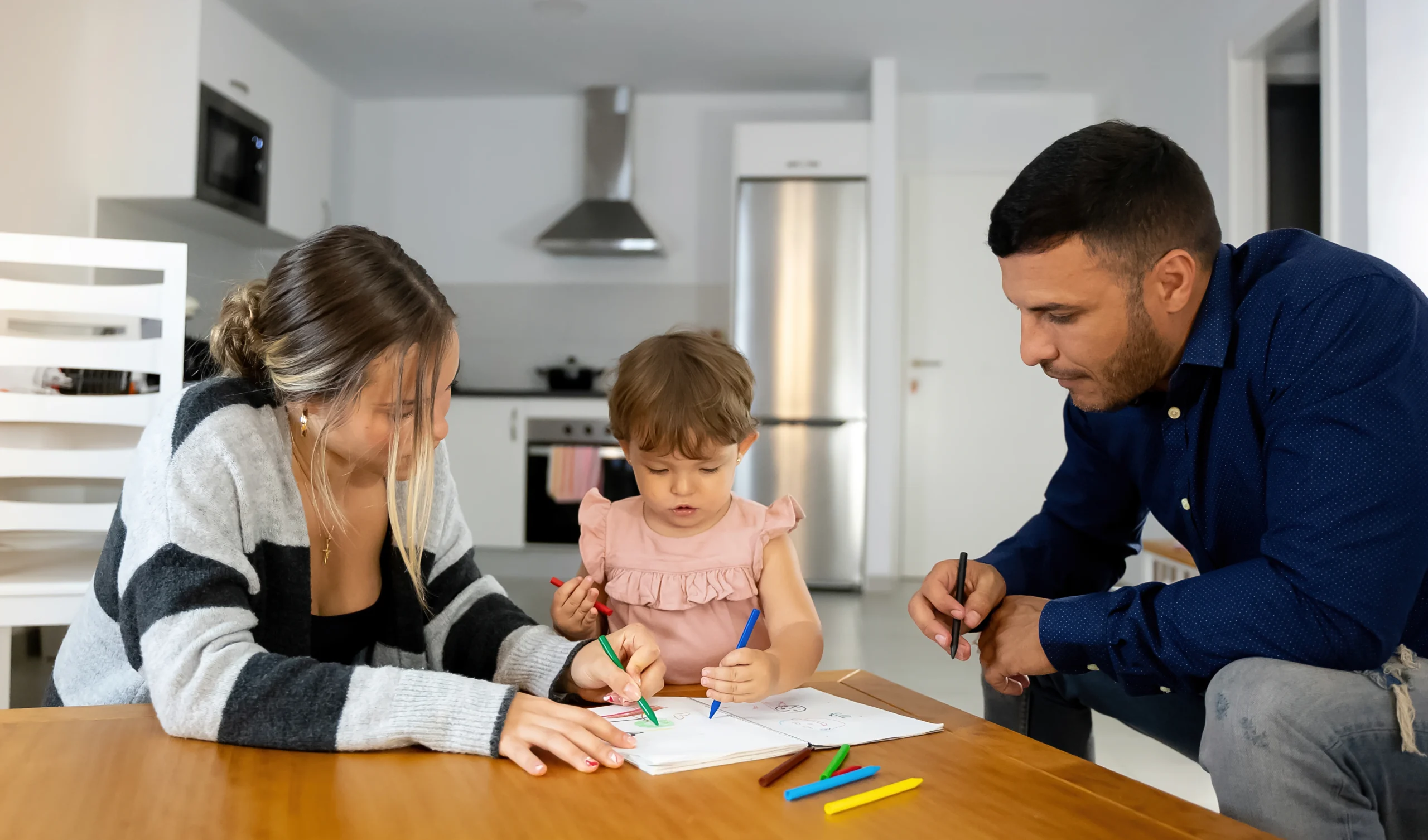 Parents engaging with their child while coloring at home, supporting key growth milestones parents should know like cognitive and motor skills development.