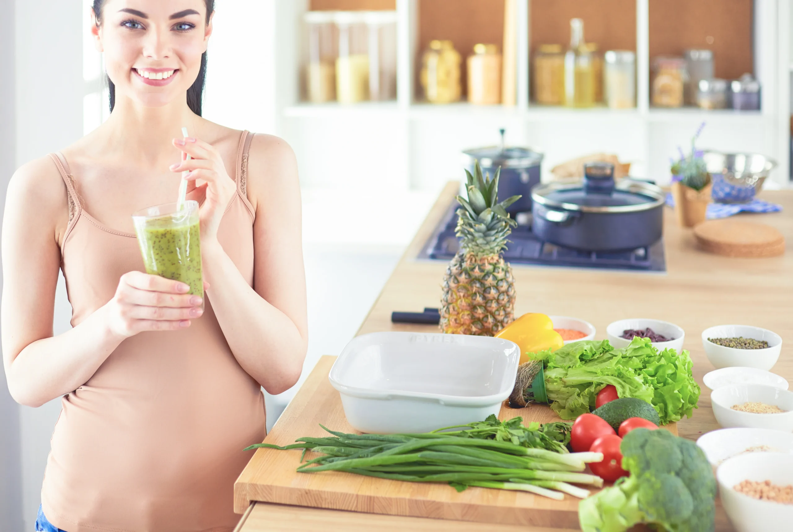 Pregnant woman enjoying a healthy smoothie in the kitchen, highlighting the importance of pregnancy nutrition essentials for women for a healthy pregnancy and baby development.