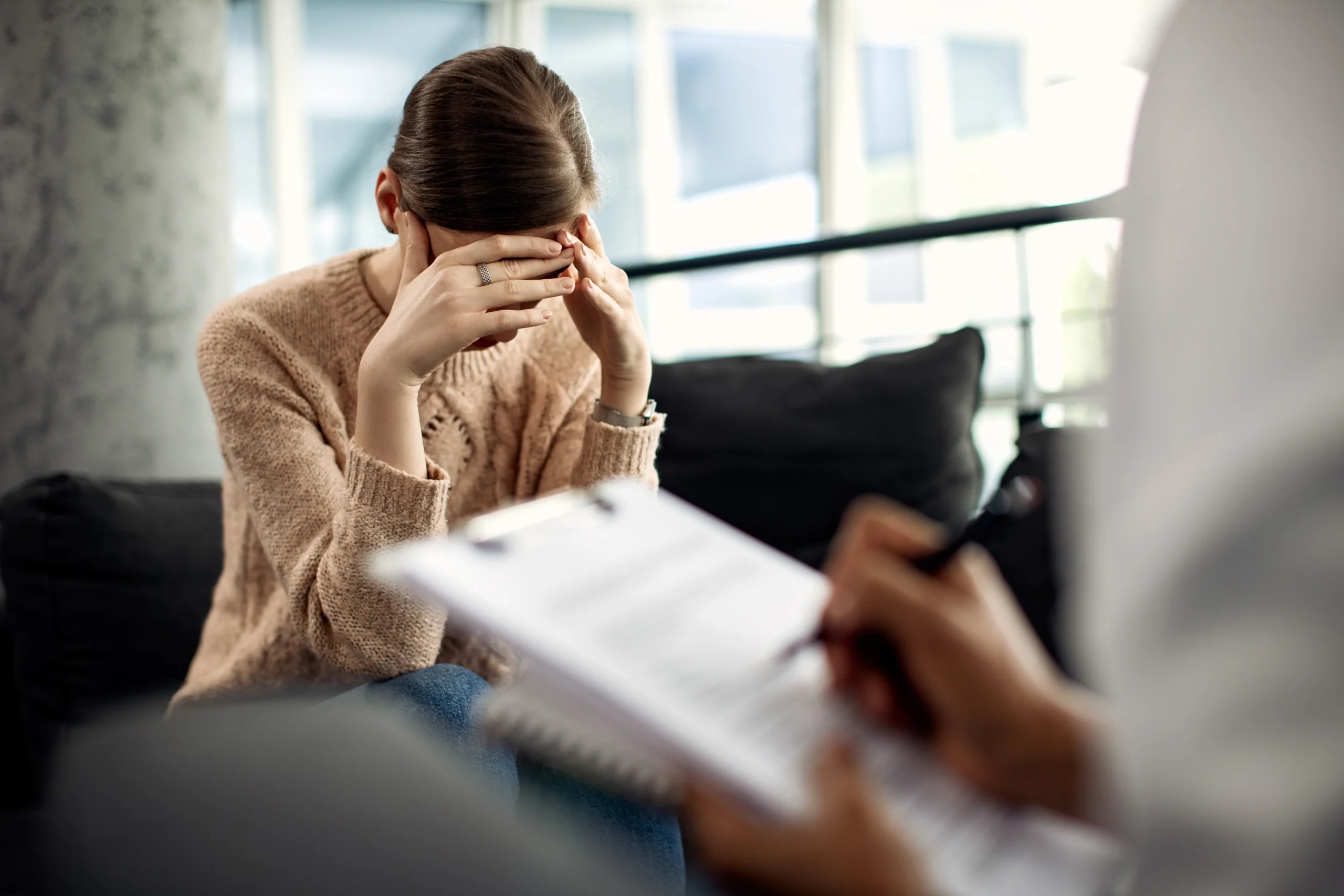 Woman in therapy session covering her face showing signs your mental health is declining and emotional stress during professional counseling support
