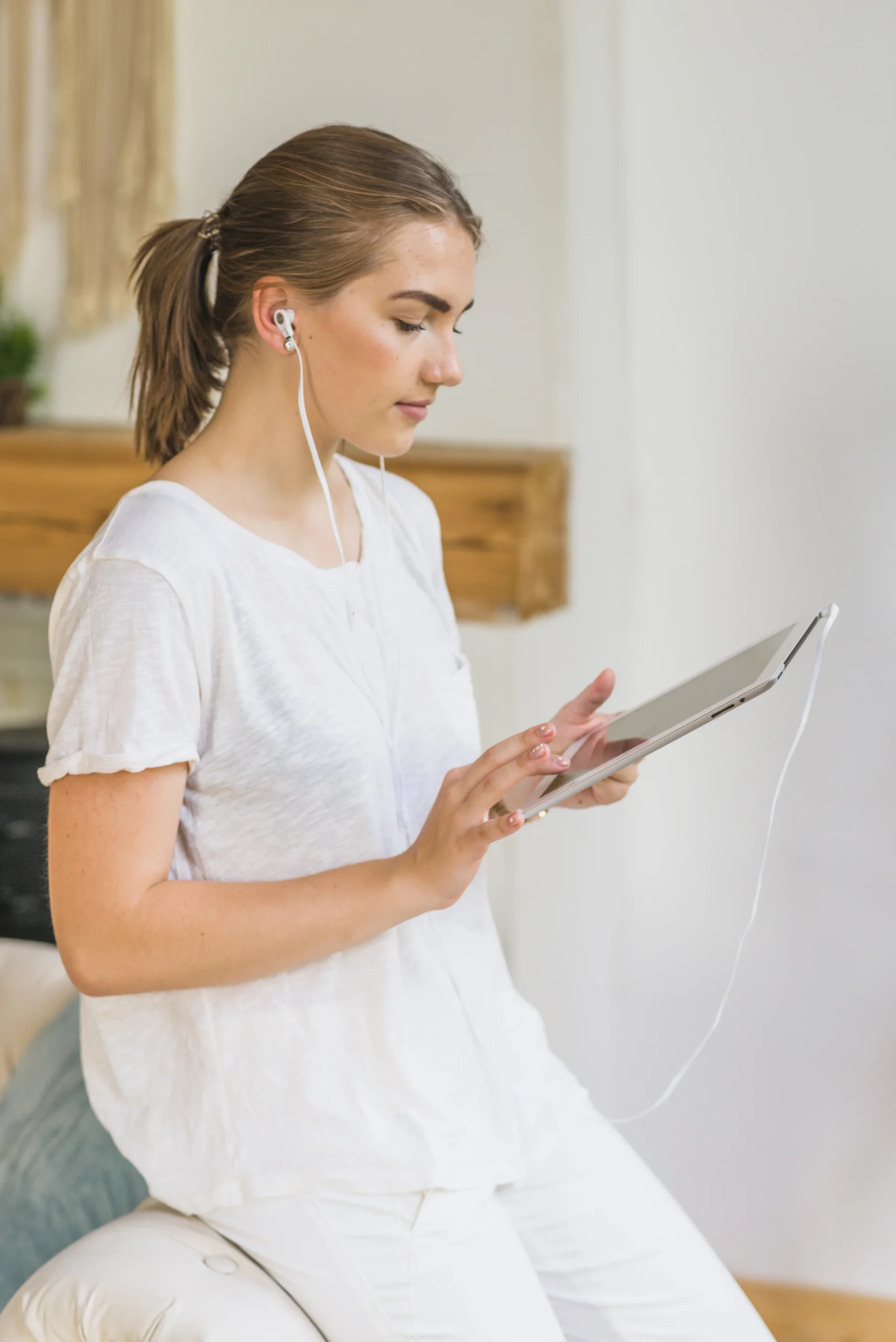 Digital mental health concept showing a young woman using a tablet and earphones to access mental health apps and online wellness support