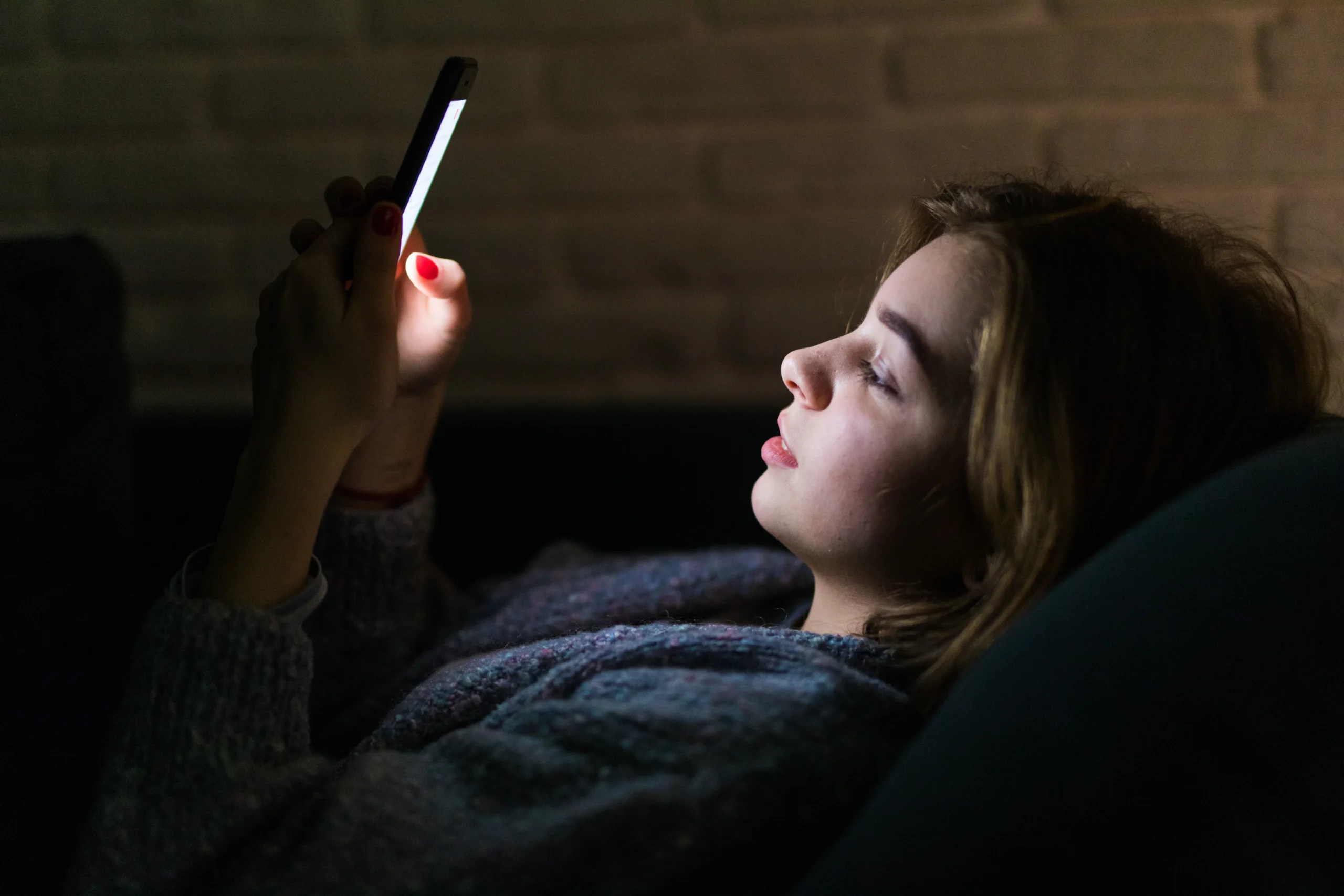 A woman using her smartphone at night, emphasizing the impact of screen time on sleep and the role of digital mental health apps in improving well-being.
