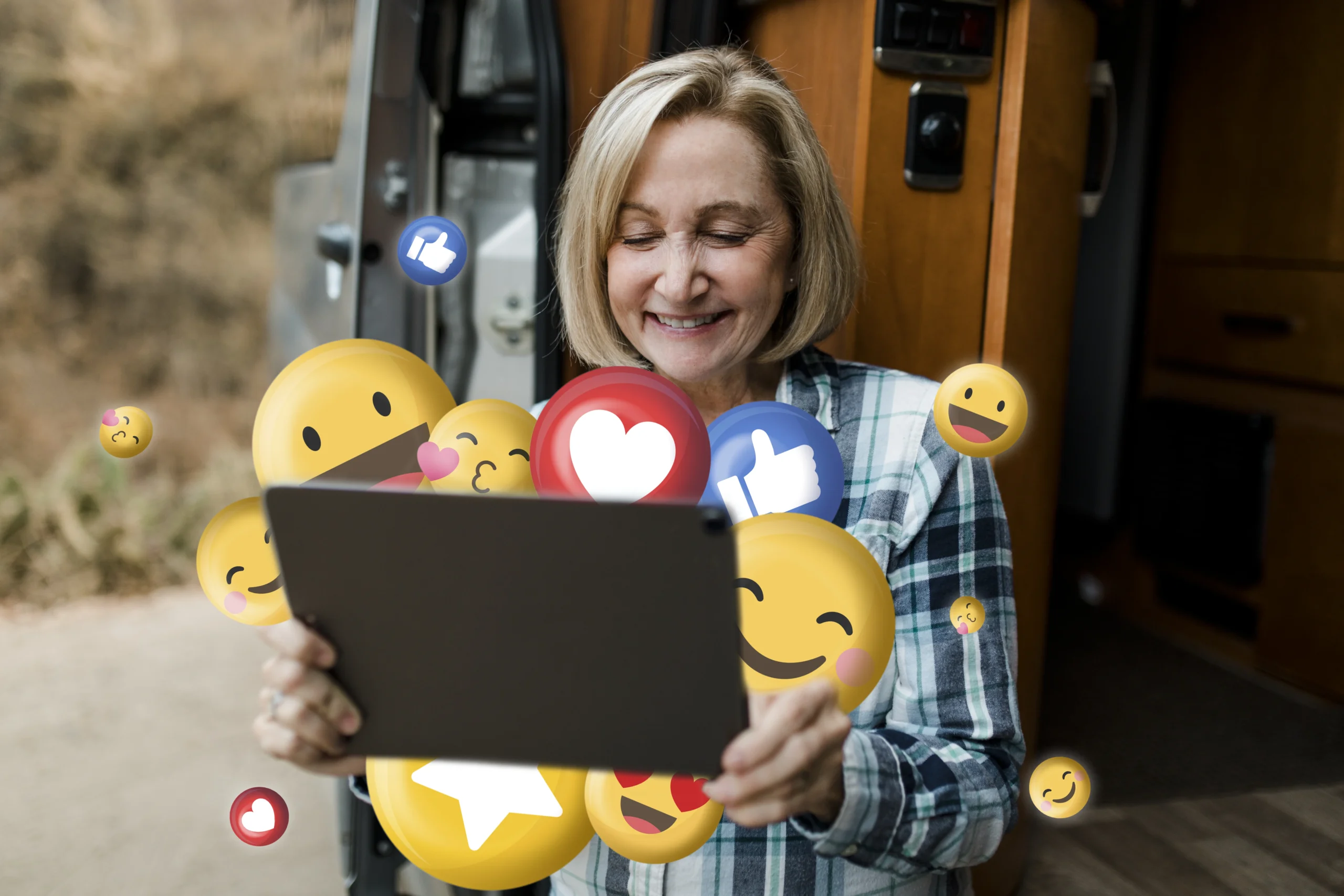 Smiling older woman using tablet surrounded by reaction emojis, reflecting positive aspects of social media and mental health.