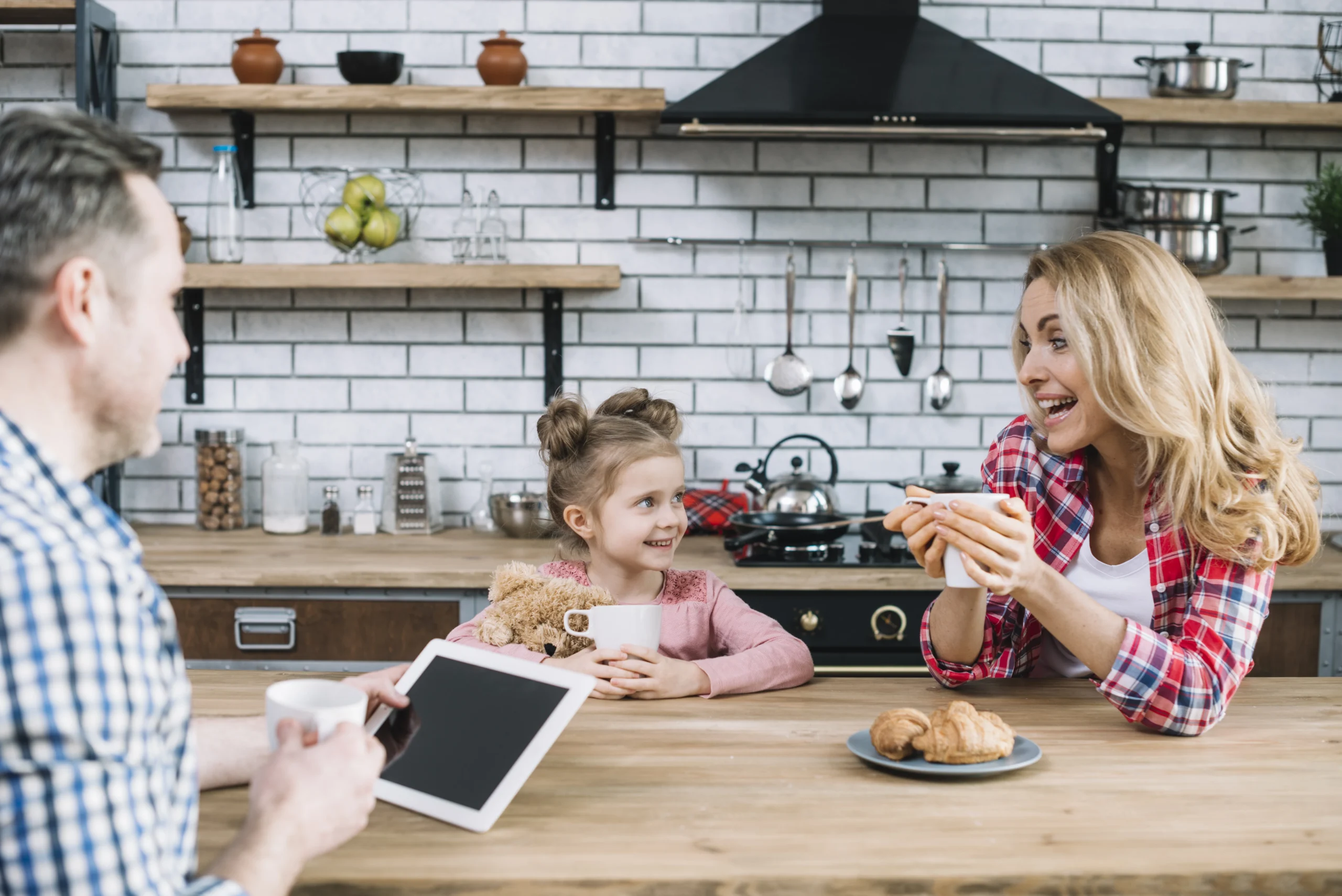 Family breakfast time in kitchen, promoting kids' mental health with positive, cheerful moments, as parents and daughter enjoy coffee and conversation.
