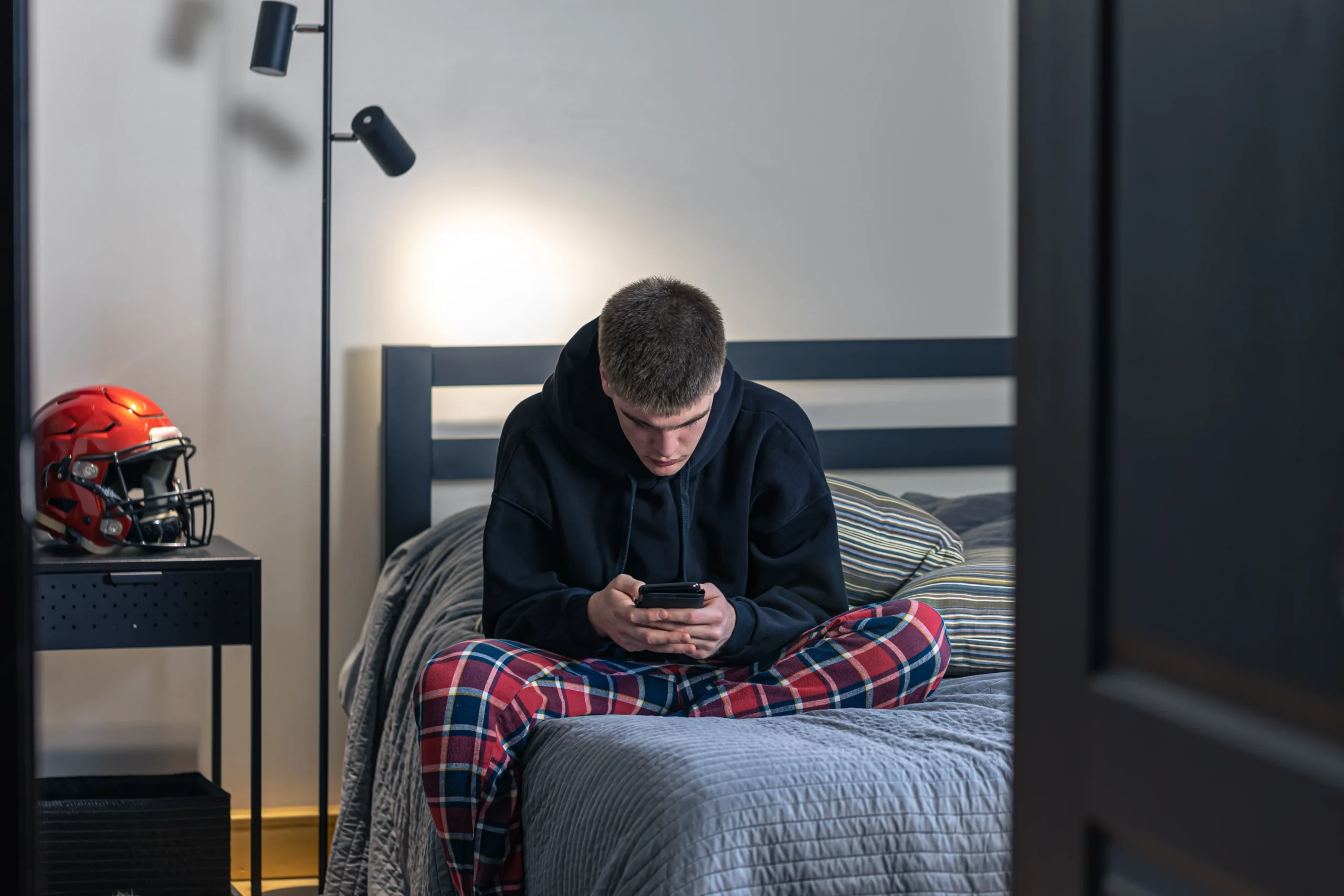 "Cyberbullying and mental health harm shown by teen boy alone using smartphone in bedroom"