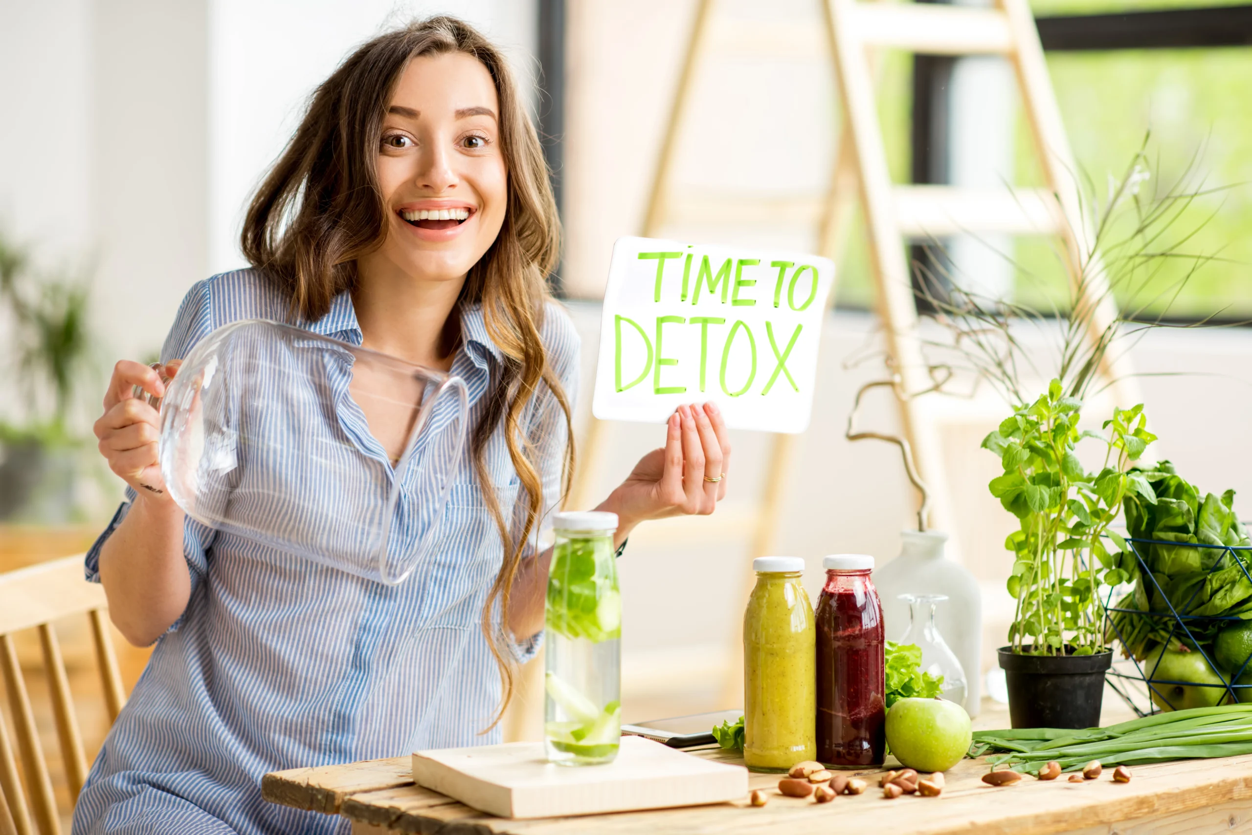 Woman holding a "Time to Detox" sign with healthy green drinks, including detox water and juices, surrounded by fresh vegetables and herbs, promoting wellness and a healthy lifestyle.