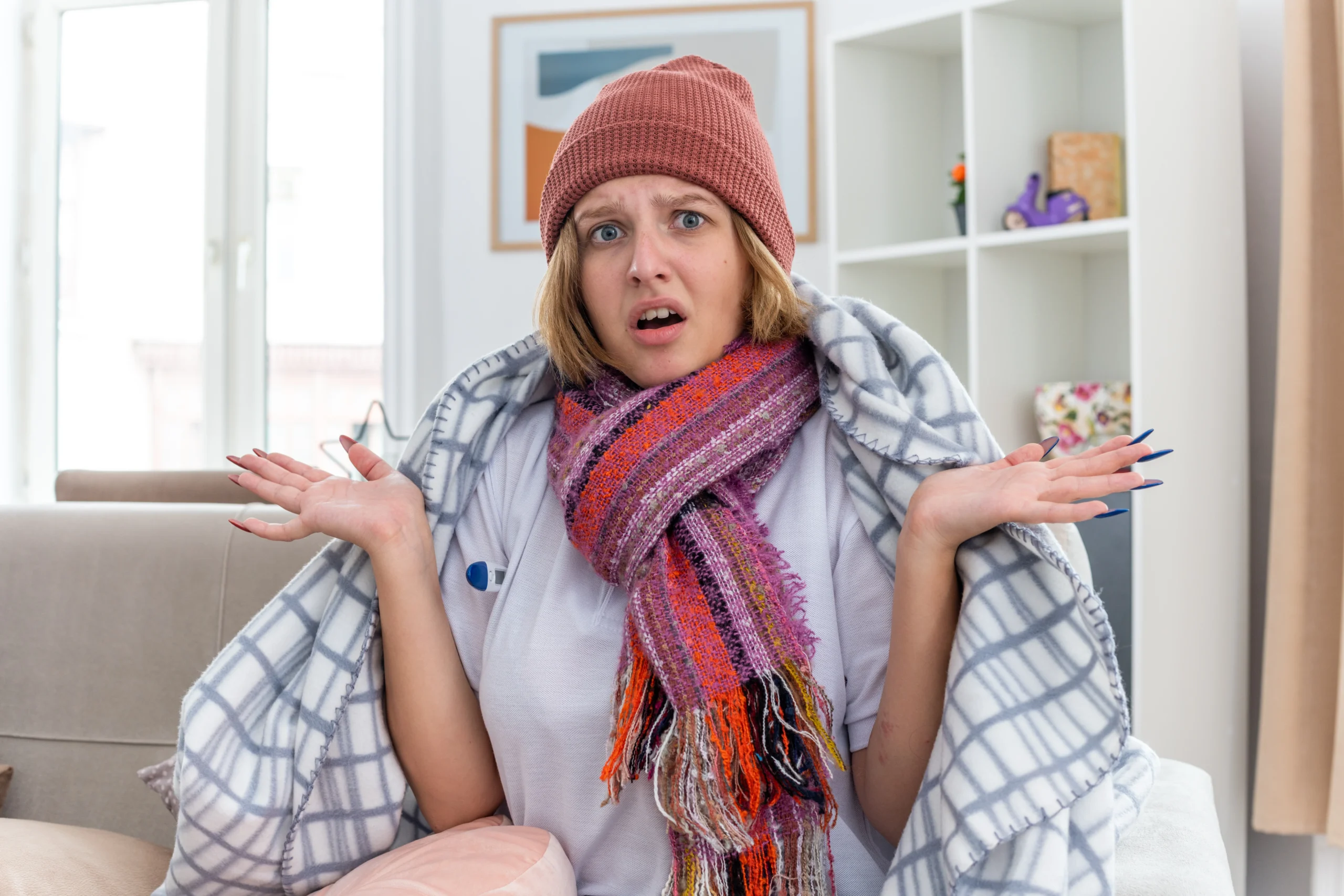Unwell woman wrapped in a blanket showing symptoms people often ignore such as fever, confusion, and flu-like discomfort at home.