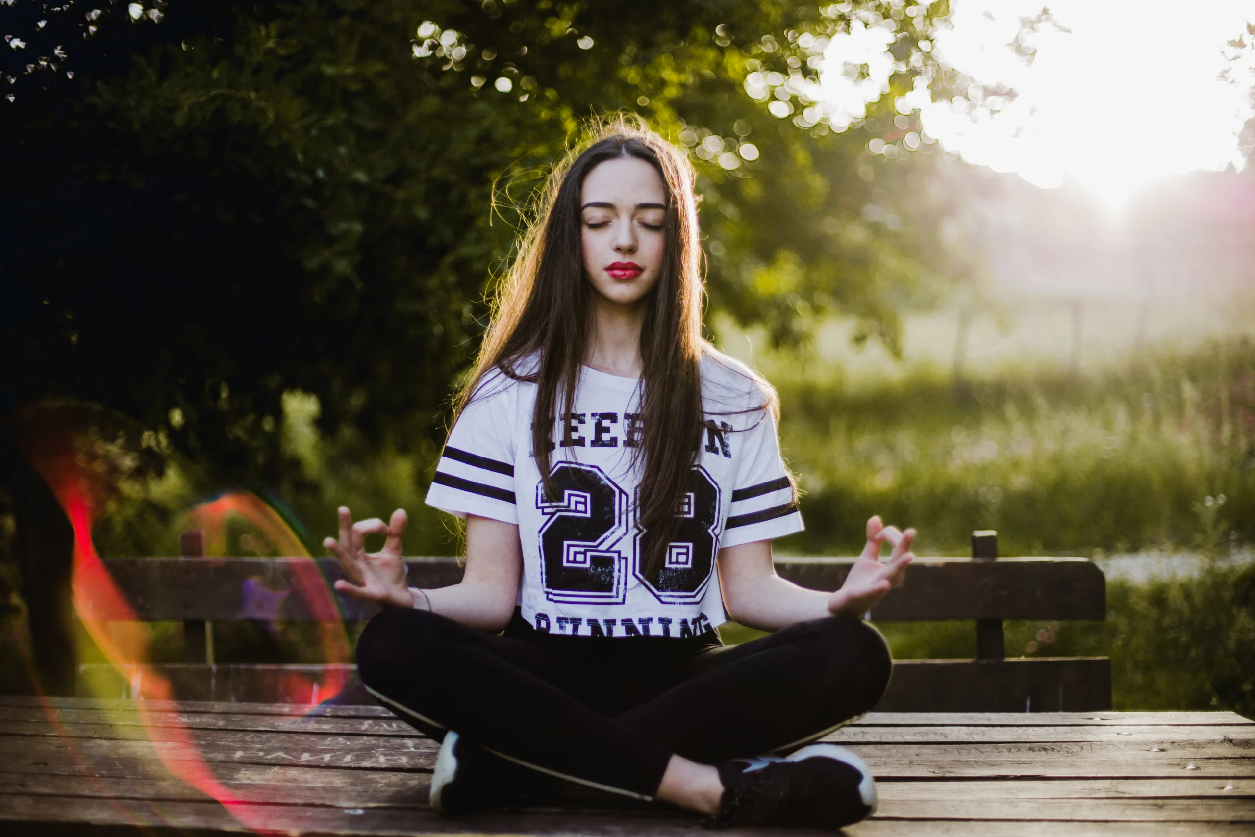 A woman meditating in a park at sunset, embodying The Holistic Guide to Wellness through mindfulness and inner peace."